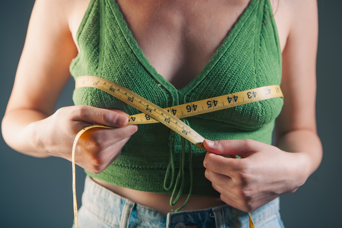Woman measuring her waist with a tape measure during a 21-day fitness protocol